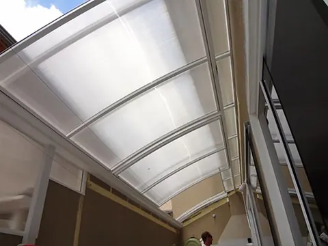 Detalhe dos trilhos e do sistema motorizado de cobertura retrátil de policarbonato