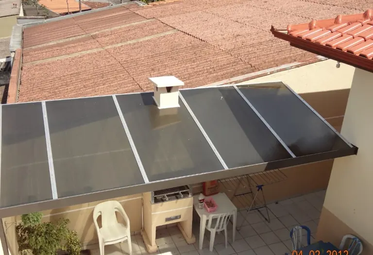 Vista superior de cobertura reta de policarbonato fumê sobre área de churrasqueira
