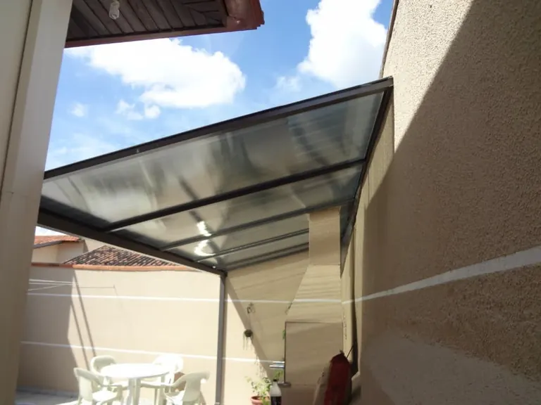 Cobertura reta com estrutura de perfil escuro sobre área de convivência externa