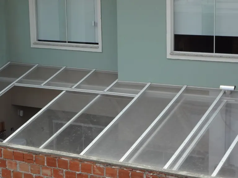 Cobertura reta de policarbonato cristal fechando área de luz entre paredes