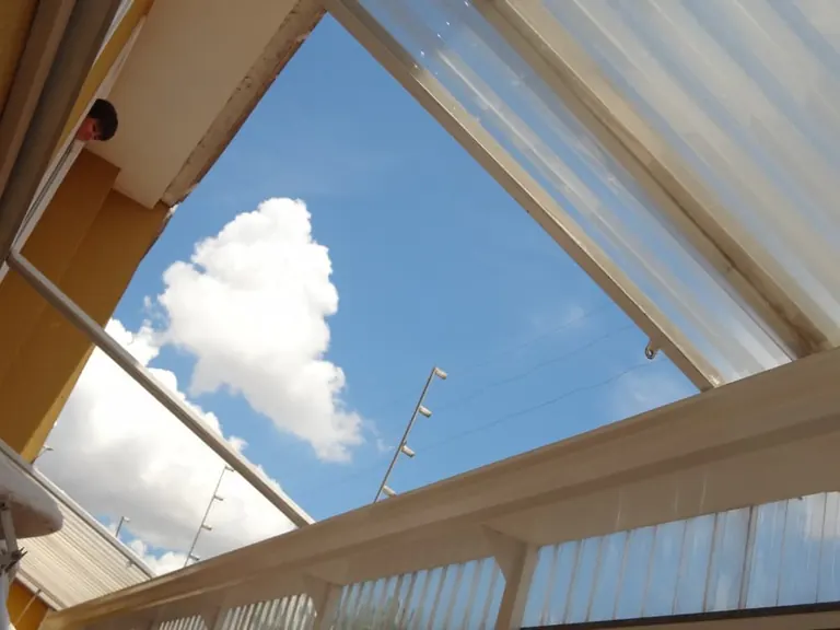 Toldo de policarbonato com estrutura em alumínio protegendo entrada comercial
